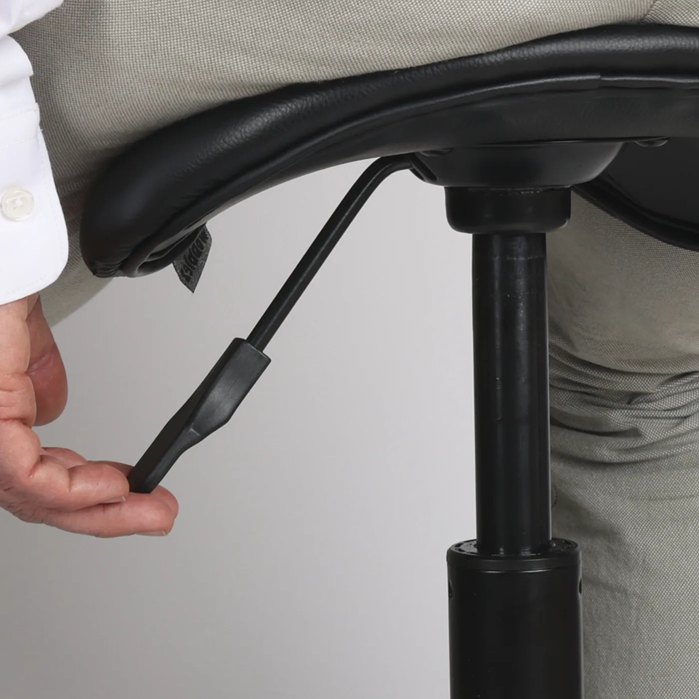 Zoom in studio photo of person adjusting a lever of the Wobblez Stable wobblestool office chair with a neutral background