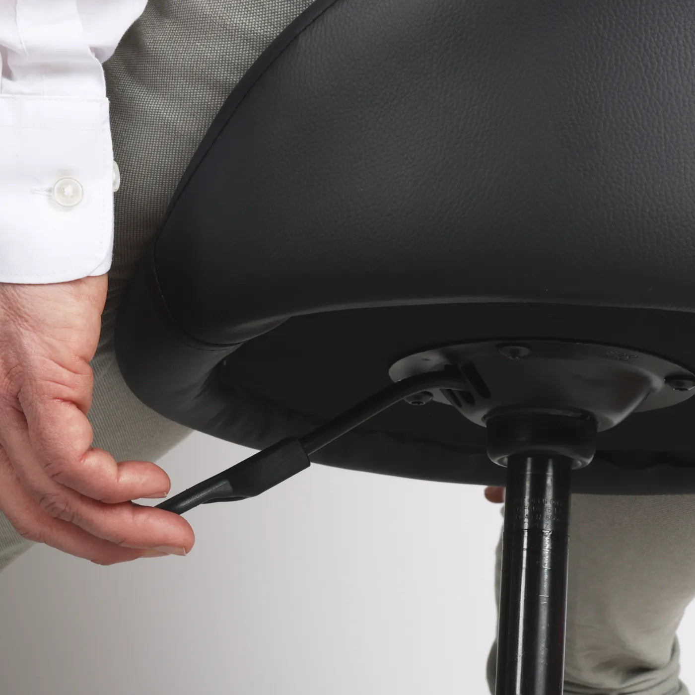 Detail photography of handle lever Wobblez Settle wobble stool person adjusting the height of faux leather black office chair with a white background