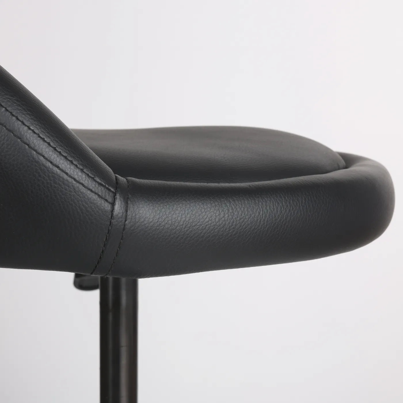 Close-up photography of the seat from black Wobblez Settle wobble stool, a faux leather black office chair with a white background