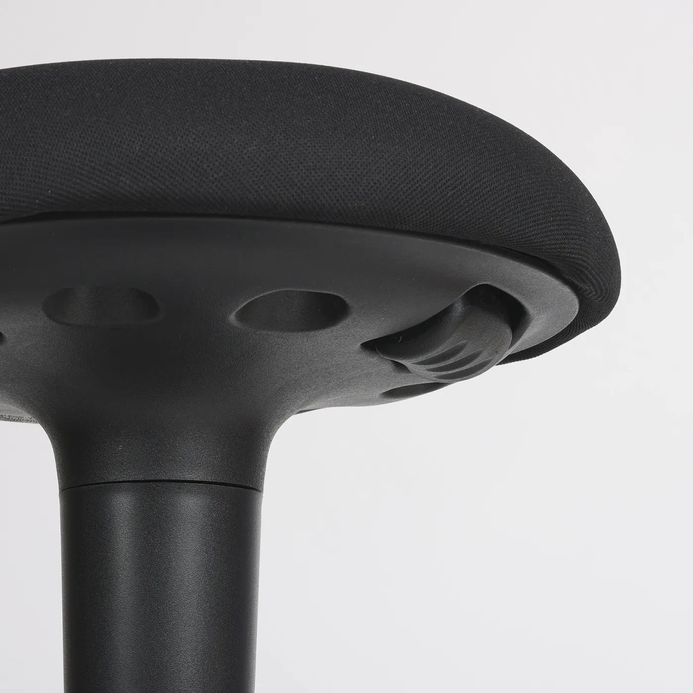 Close-up studio photo diagonal bottom view of a part of the seat of the Wobblez Spine wobble stool in black and the knob visible on a neutral white grey background