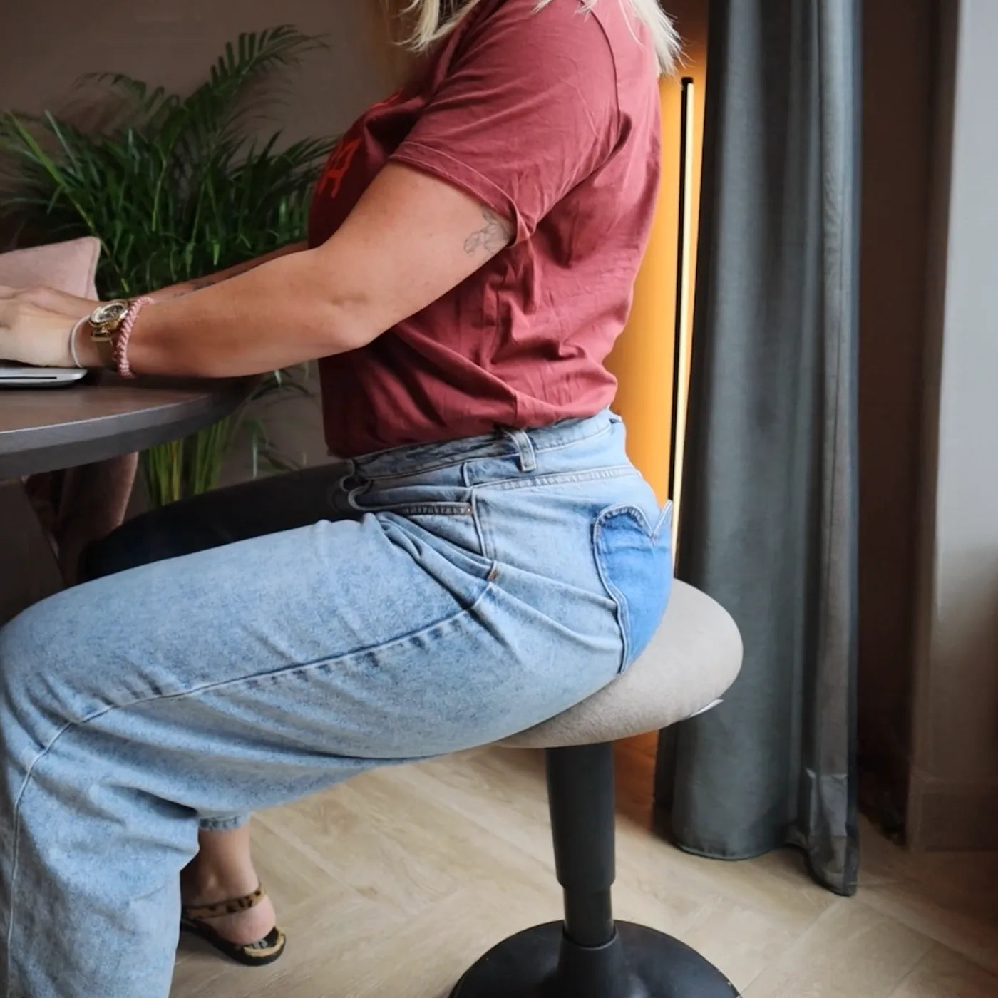 Woman sitting an a black-taupe Spine Wobblez wobble stool showcasing sitting posture while working at the table