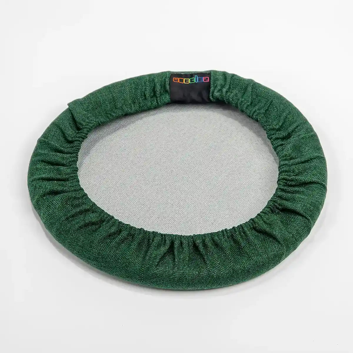 Bottom view studio photography of Forest Green Wobblez Skins, a premium seat stool cover for Spine and Savvy wobble stools with a brand label on the edge on white background