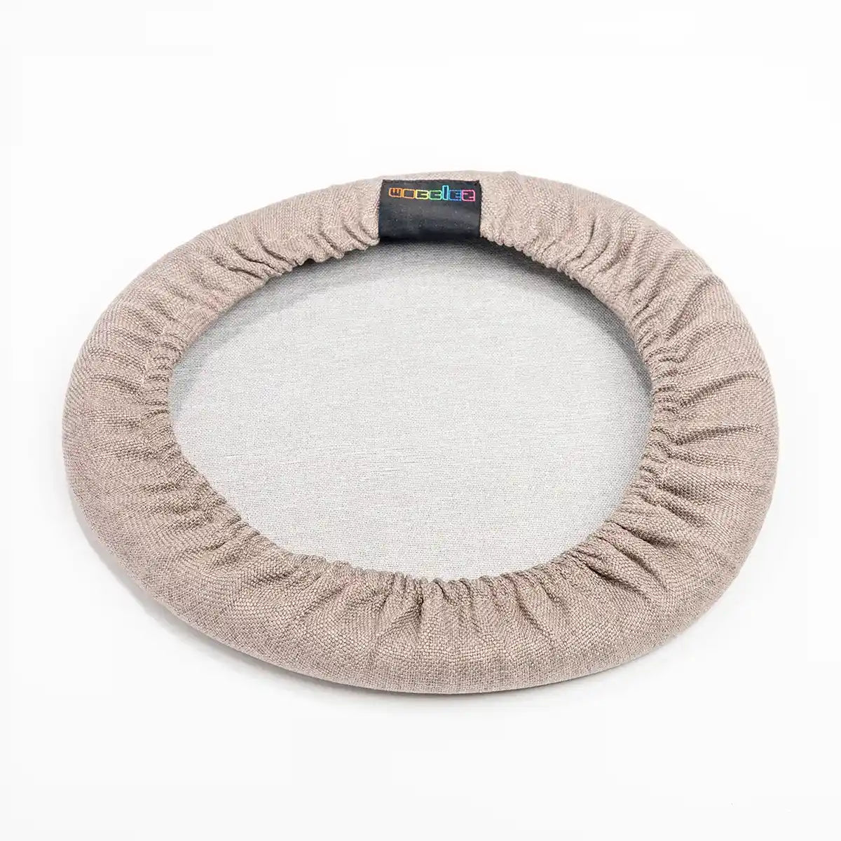 Bottom view studio photography of Taupe Wobblez Skins, a premium seat stool cover for Spine and Savvy wobble stools with a brand label on the edge on white background