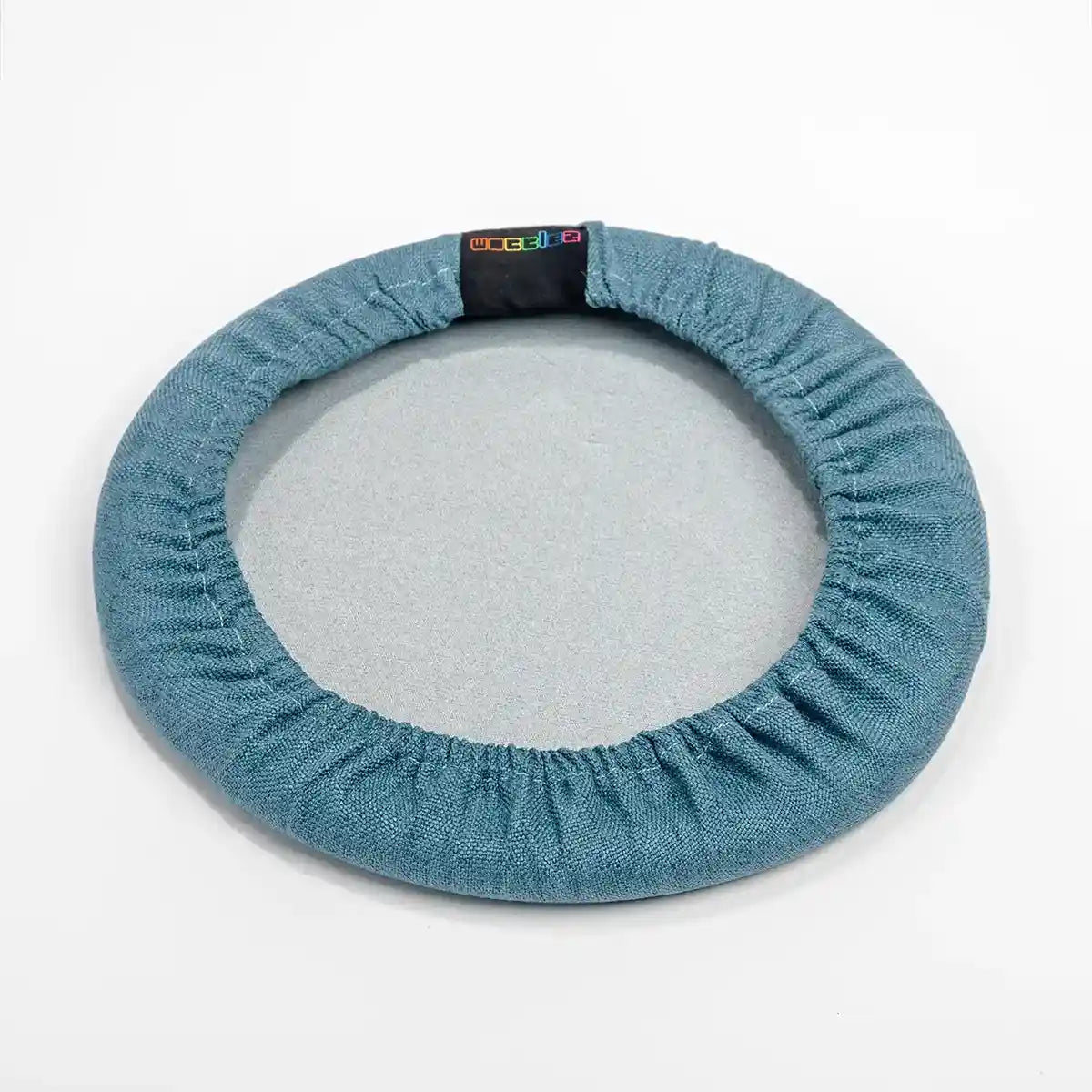 Bottom view studio photography of Blue Wobblez Skins, a premium seat stool cover for Spine and Savvy wobble stools with a brand label on the edge on white background