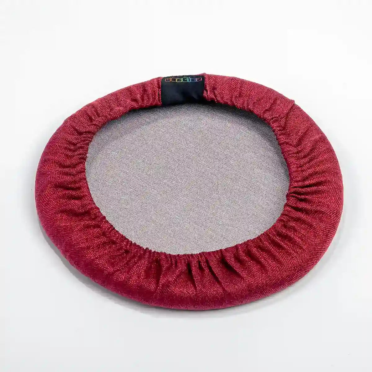 Bottom view studio photography of Bordeaux Red Wobblez Skins, a premium seat stool cover for Spine and Savvy wobble stools with a brand label on the edge on white background