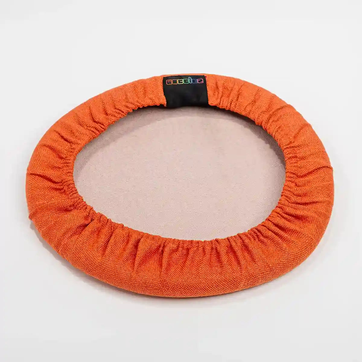 Bottom view studio photography of Orange Coral Wobblez Skins, a premium seat stool cover for Spine and Savvy wobble stools with a brand label on the edge on white background
