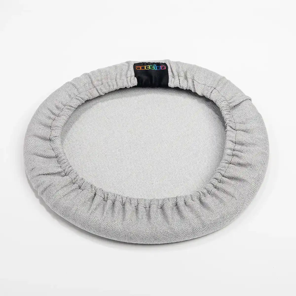 Bottom view studio photography of Metallic Grey Wobblez Skins, a premium seat stool cover for Spine and Savvy wobble stools with a brand label on the edge on white background