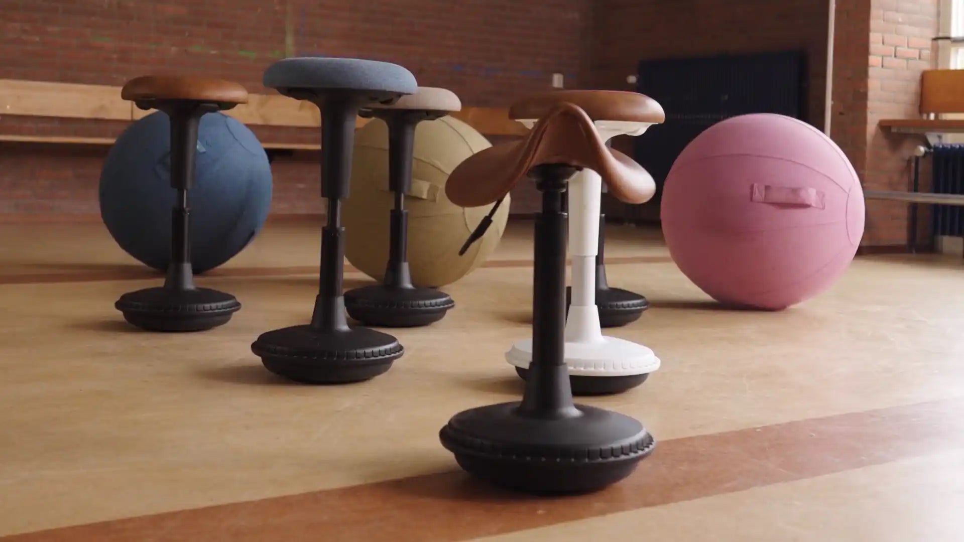 Set of balance Wobblez stools and balls ,standing in a room with brick walls.